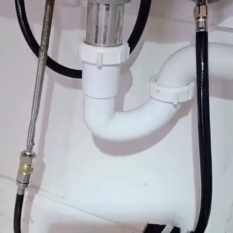 Rebuilt PVC P-trap and disposal tailpiece under a kitchen sink