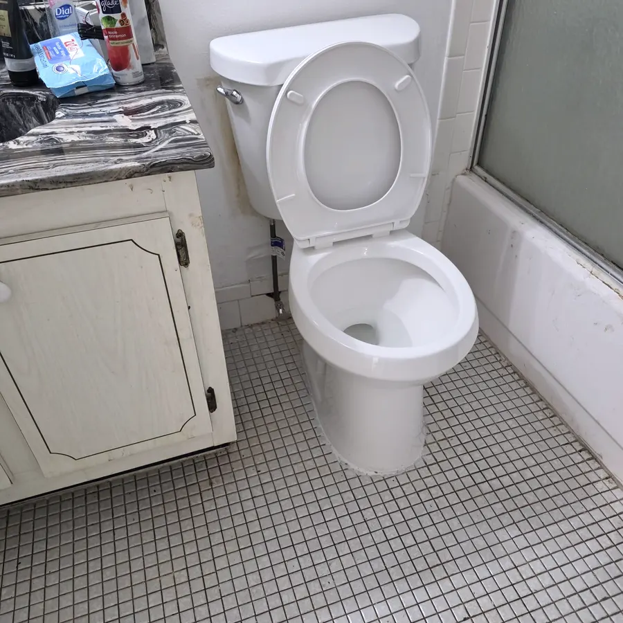 A newly set toilet sealed to a tiled bathroom floor